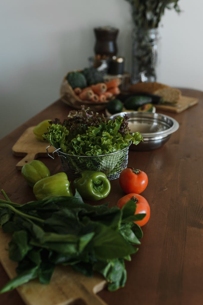 A selection of fresh vegetables including tomatoes, lettuce, and peppers on a wooden table.