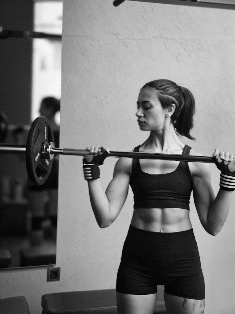 Athletic woman exercising with a barbell for strength training in a gym.